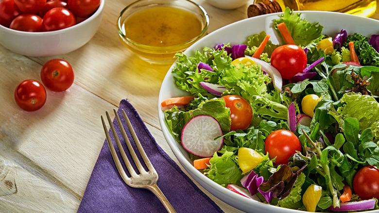 Salad in a bowl with cherry tomatoes, radishes, and sliced carrot