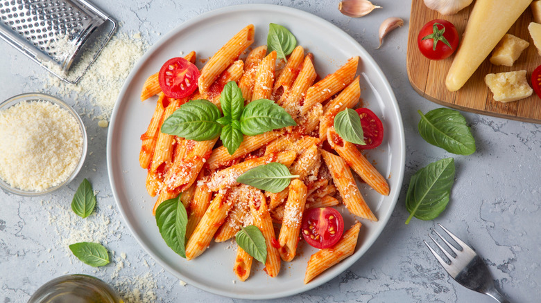 Plate of penne pasta with tomato sauce and basil leaves