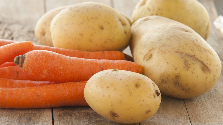 Potatoes and carrots on wooden table