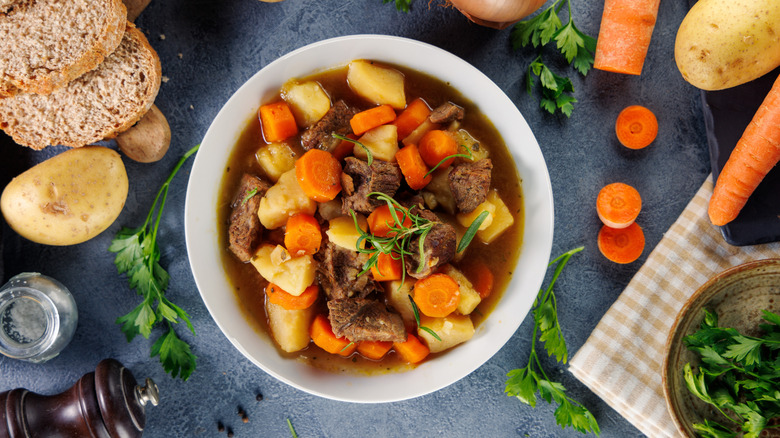 White bowl of beef stew surrounded by various ingredients