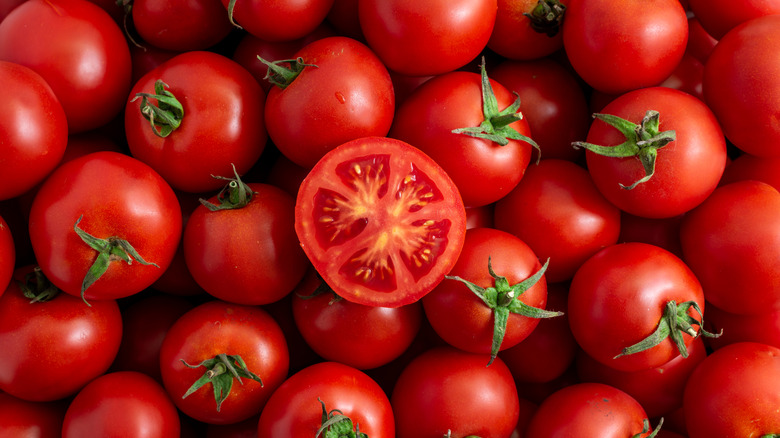 Halved tomato on top of heap of tomatoes