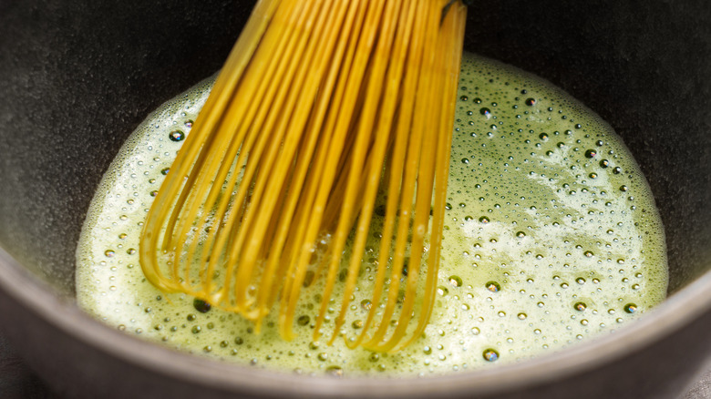Closeup of a bamboo chasen in a frothy cup of matcha