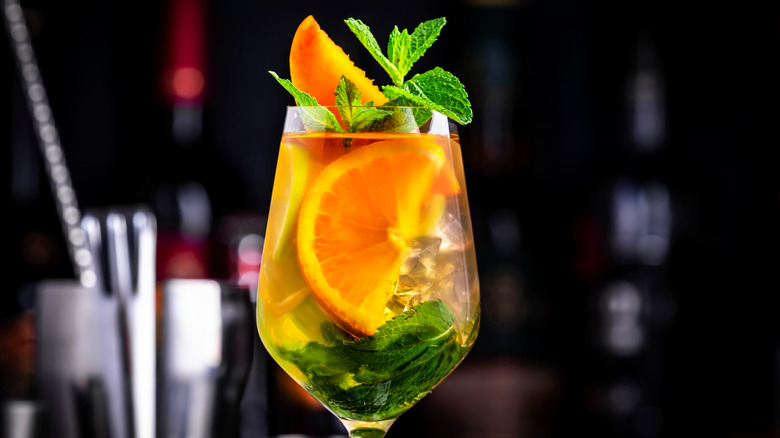 White sangria in wine glass on bar garnished with mint and orange slices
