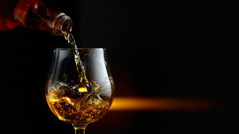 Brandy being poured into glass on dark background