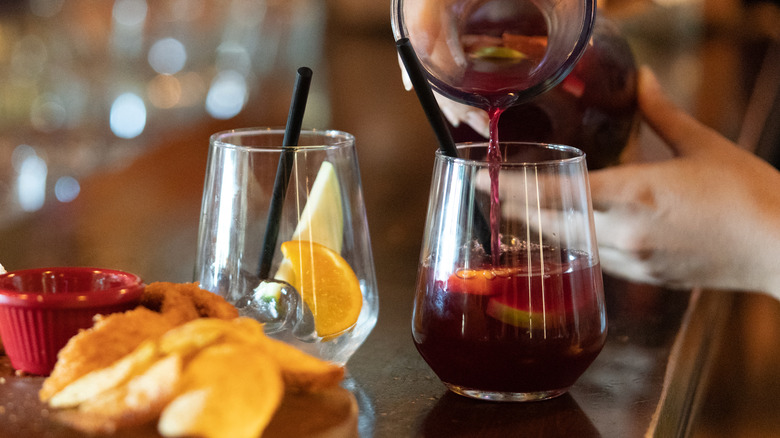 Bartender pouring sangria into stemless wine glass
