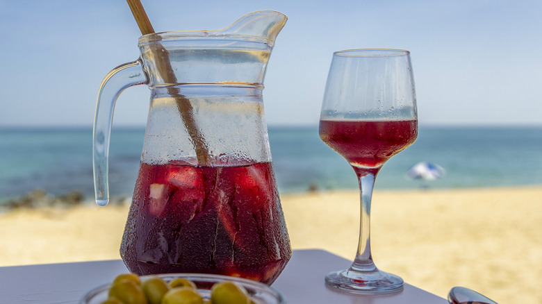 Sangria in pitcher and glass on table at a sandy beach