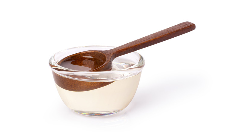 Simple syrup in glass bowl with wooden spoon on white background