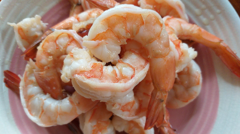 Overcooked shrimp on pink and white plate