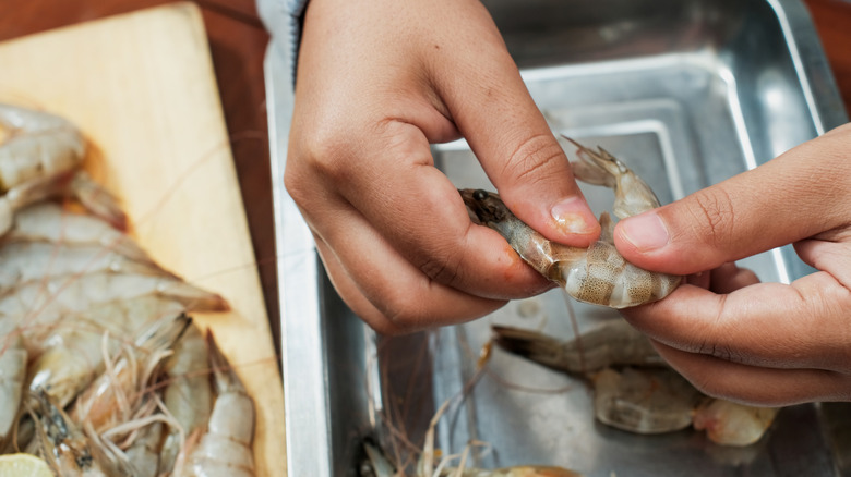 Hands peeling raw shrimp