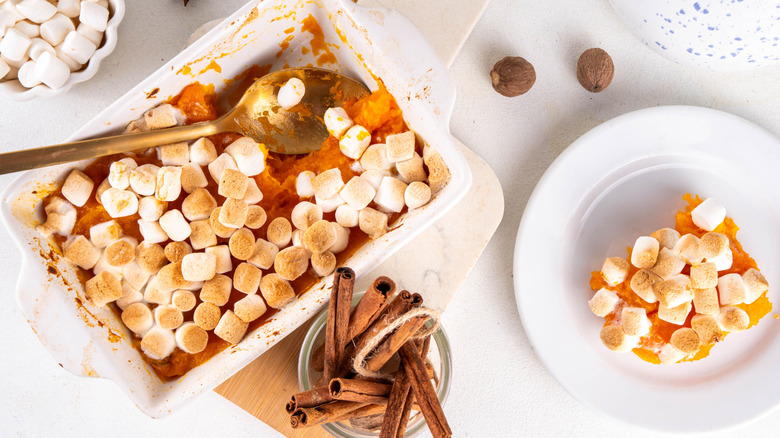 Sweet potato casserole topped with marshmallows in dish and on white plate