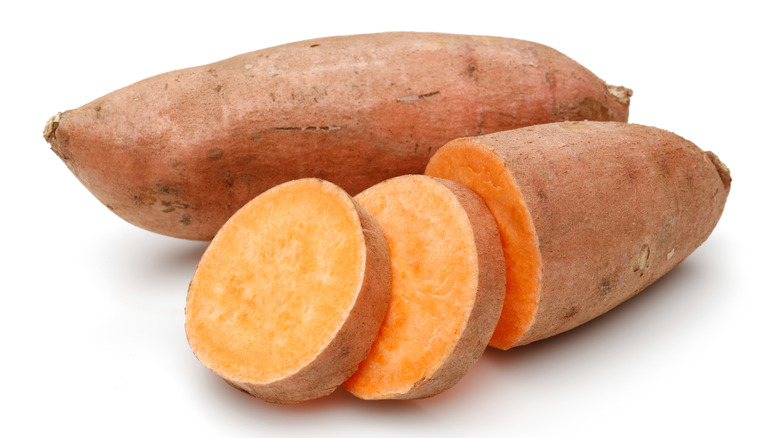 Chopped and whole sweet potatoes on white background