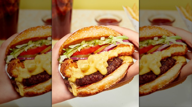 Hands holding burger with fried cheese at The Cheesecake Factory