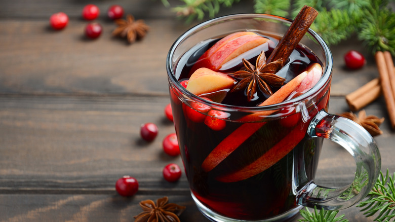 Mug of mulled wine with garnishes on wooden table