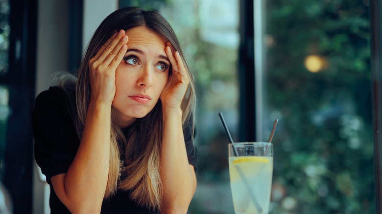 A woman sitting alone at a restaurant table looking embarrassed