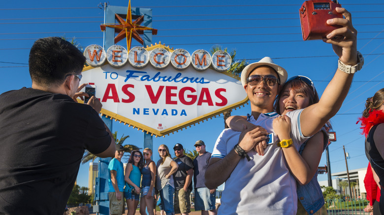 Tourists taking selfies at the iconic 'Welcome to Fabulous Las Vegas" sign