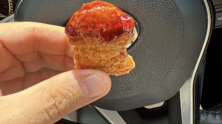 Hand holding Wendy's chicken nugget covered in sauce
