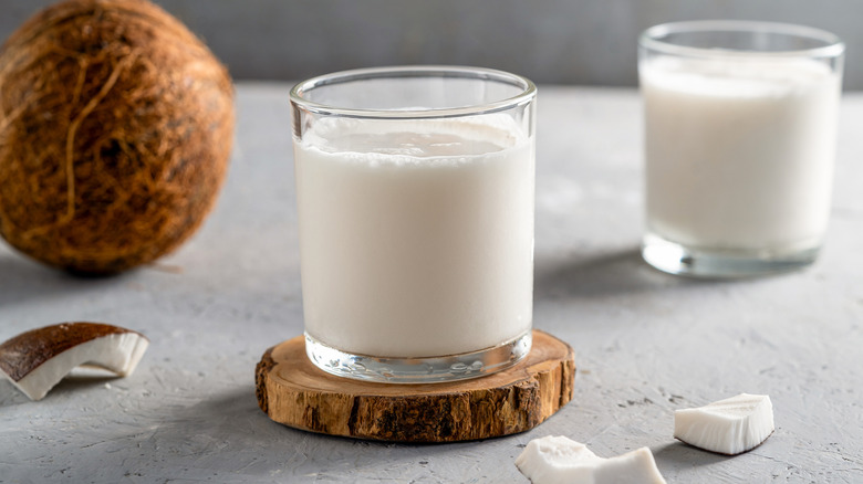 Coconut milk in clear glass on wooden coaster