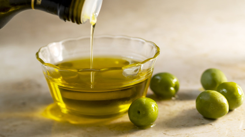 Olive oil in small glass bowl with olives