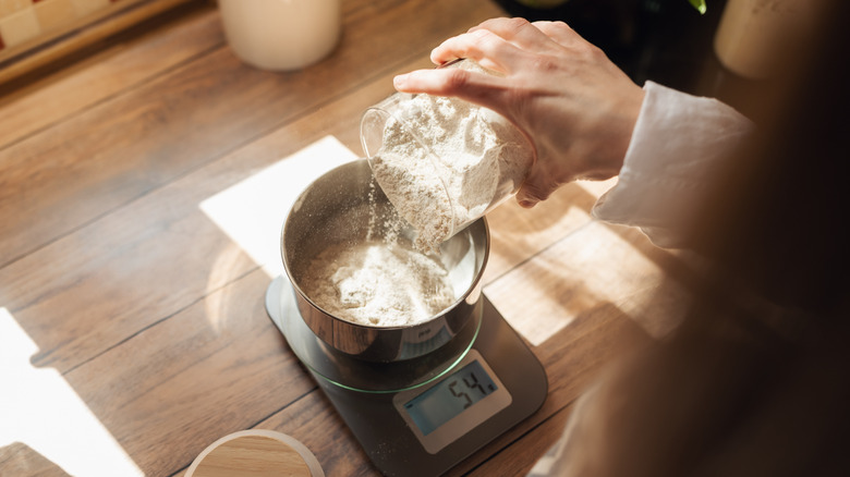 person weighing flour on a scale