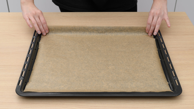 person lining a baking sheet with parchment paper