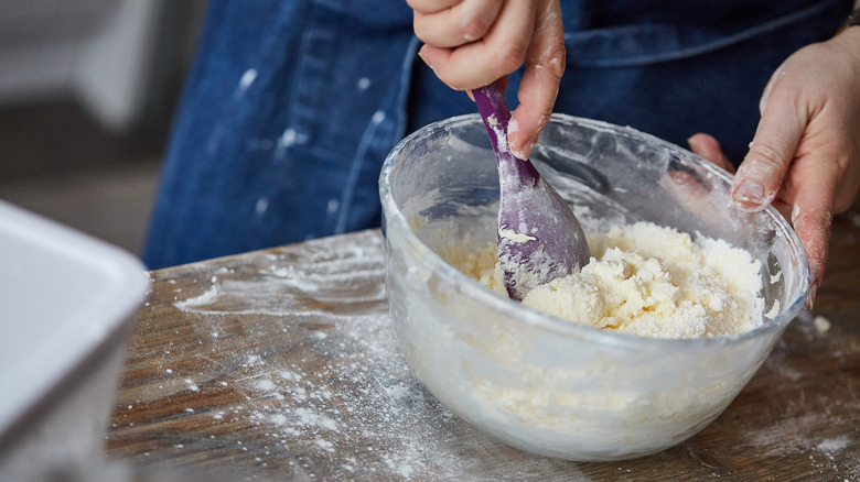 A person mixing dough in a bowl