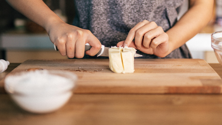 A woman cutting butter on a cutting board