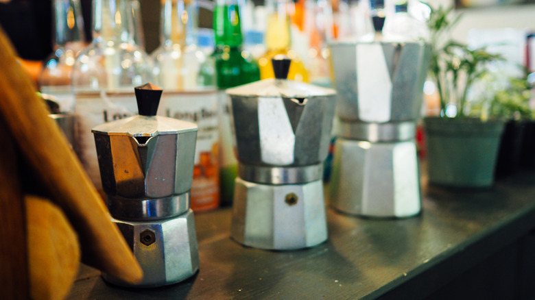 Three Moka pots of various sizes lined up on a countertop.