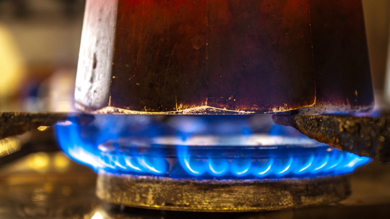 Close up of a moka pot over flames on a stove.