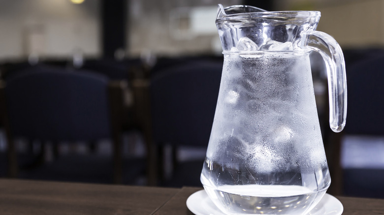 Ice cold water in a pitcher on a table.
