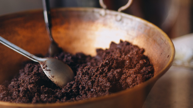 Coffee grinds in a large bowl with two spoons.