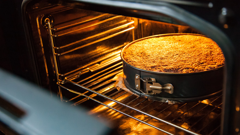 Cake baking in an oven with lights on and door open