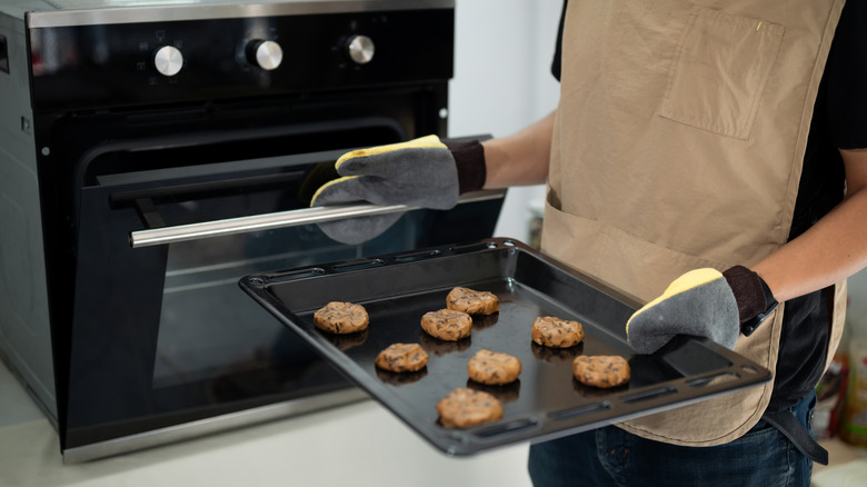 Person putting tray of chocolate chip cookies in oven