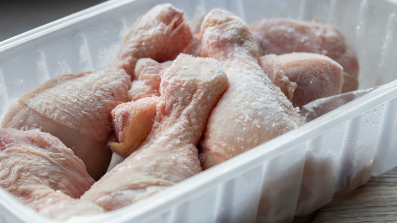 Frozen chicken drumsticks in plastic tub