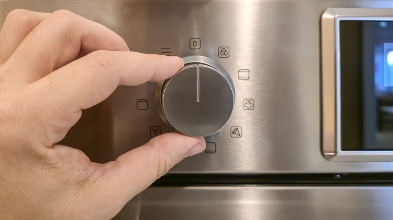 Hand turning dial on a stainless steel oven