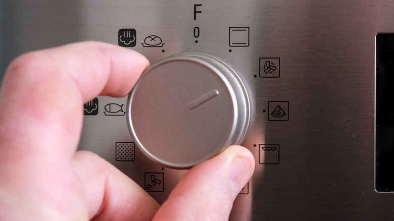 Hand turning oven dial to fan setting