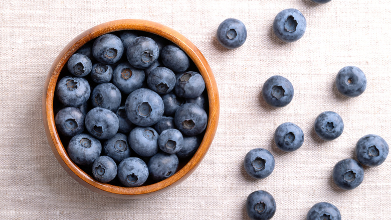 Blueberries in wooden bowl with some spilling out