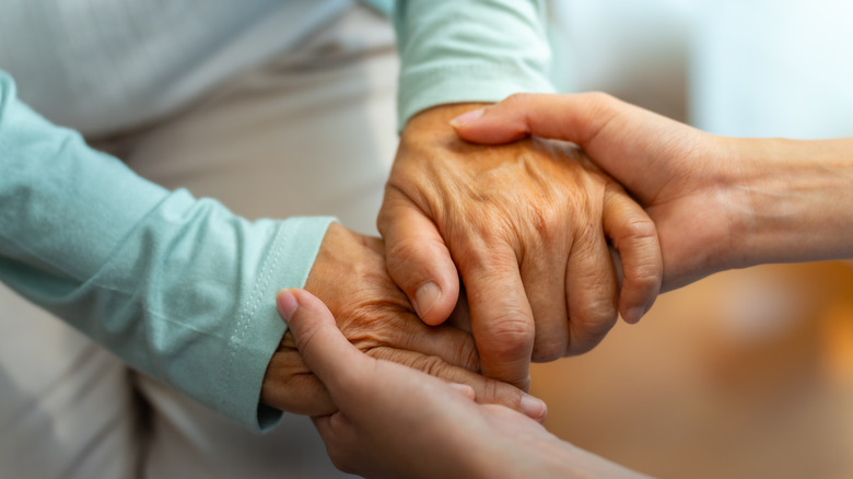 Elderly woman has hands held by doctor