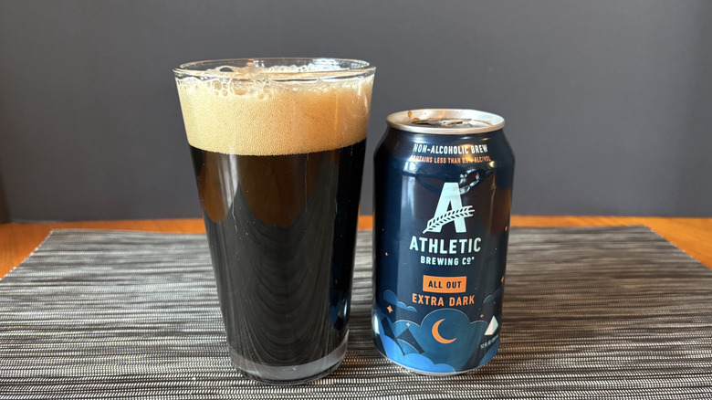 Athletic all out extra dark brew in can and glass on dark background