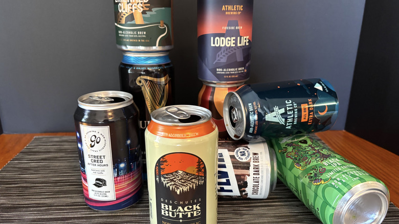 A variety of empty non-alcoholic beer cans on a black background