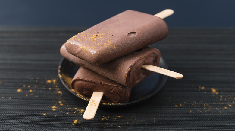 Chocolate pudding popsicles with orange powder sprinkled on them