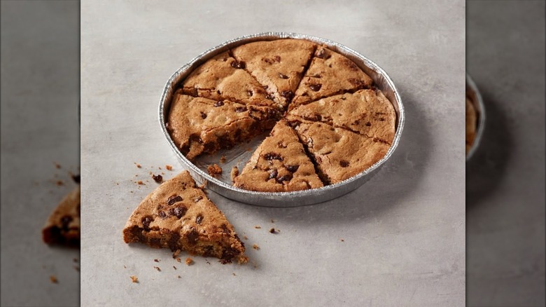 Papa John's Chocolate Chip Cookie inside foil dish with slice taken out