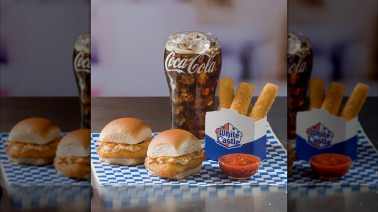 Two White Castle Garlic Parm Chicken Sliders next to cup of Coca-Cola and box of mozzarella sticks on blue and white checkered table mat