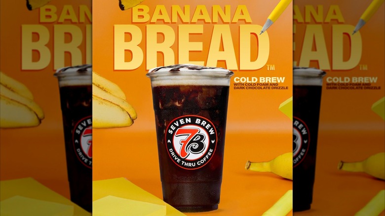 7 Brew Coffee Banana Bread Cold Brew drink with creamy topping surrounded by bananas against orange backdrop