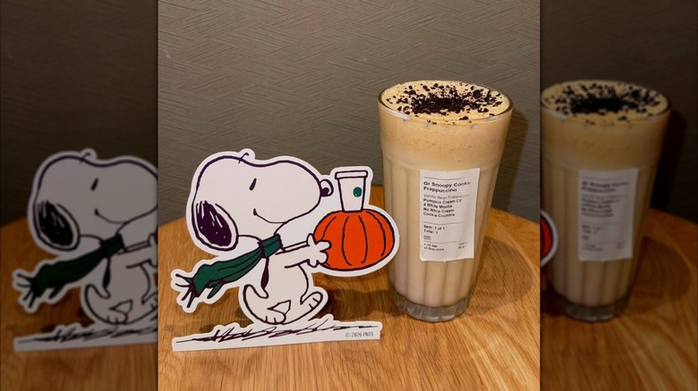Starbucks Snoopy Cookie Frappuccino in glass next to Peanuts Snoopy cardboard cutout