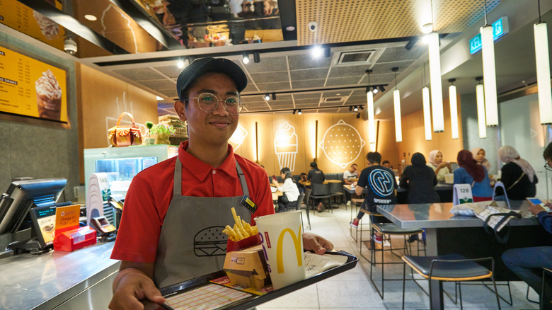 McDonald's worker carrying a tray with food inside the restaurant