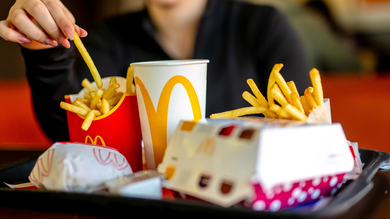 Hand taking fry from full tray of McDonald's food