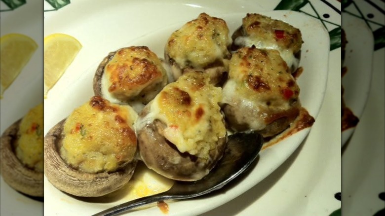 White plate with stuffed mushrooms and metal spoon, mirrored image