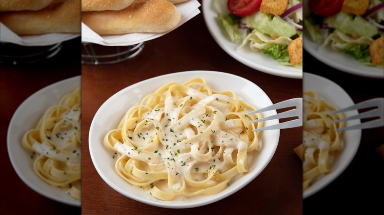 Close up of fettucine alfredo in white bowl with fork, mirrored image