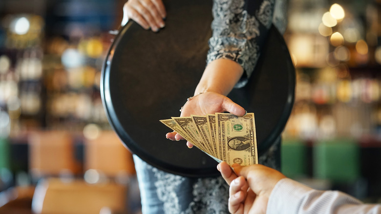 The hand of a server takes a tip