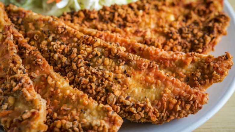 A close-up photograph of breaded and fried catfish fillets